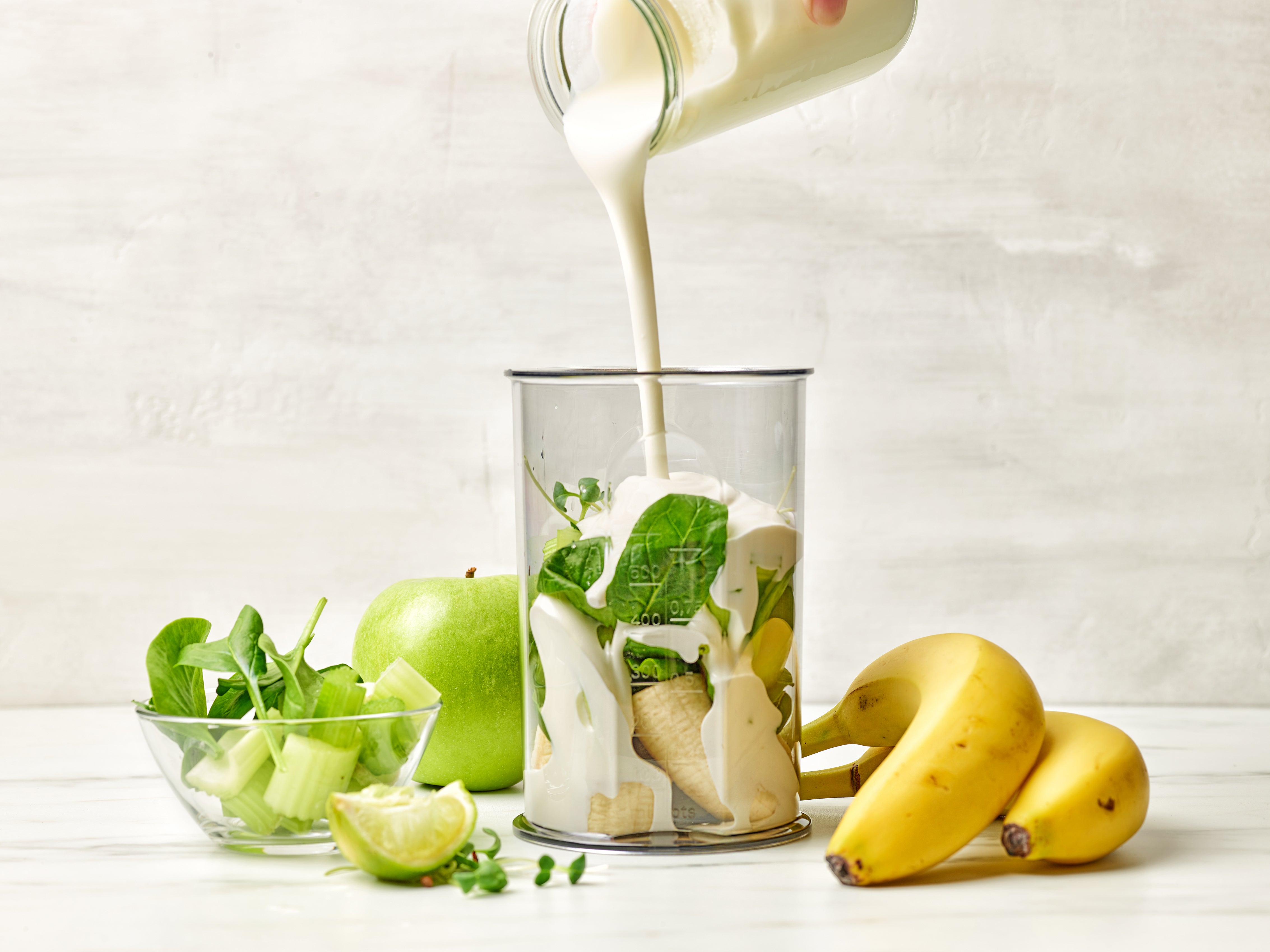 Ein Shake aus Joghurt, Apfel, Spinat und Bananen wird in einem Glas angerichtet.