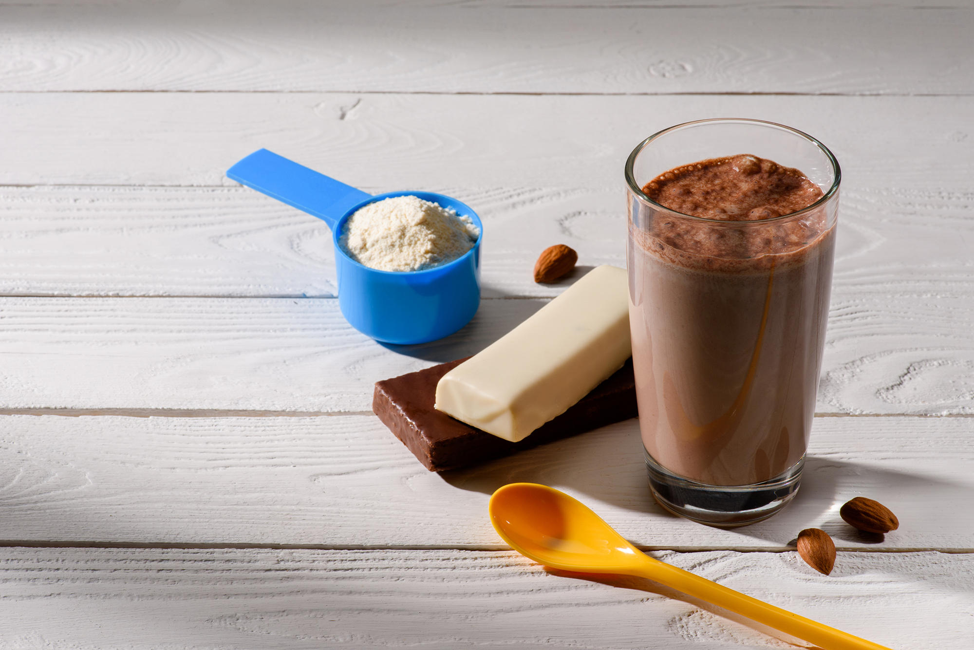 Ein Glas mit einem Proteinshake und zwei Proteinriegel daneben