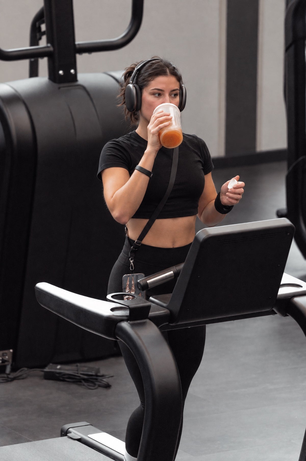 Athletin trinkt Recovery-Shake auf dem Laufband im EVO LAND
