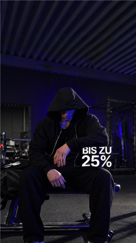 Athlet im schwarzen Hoodie sitzt im dunklen Gym, daneben Bis zu 25 %